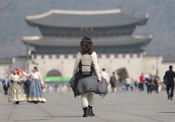 서울 낮 최고 기온이 23도로 따뜻한 날씨가 예보된 23일 서울 광화문광장에서 한 시민이 외투를 허리에 묶은 채 걸어가고 있다./사진=연합뉴스
