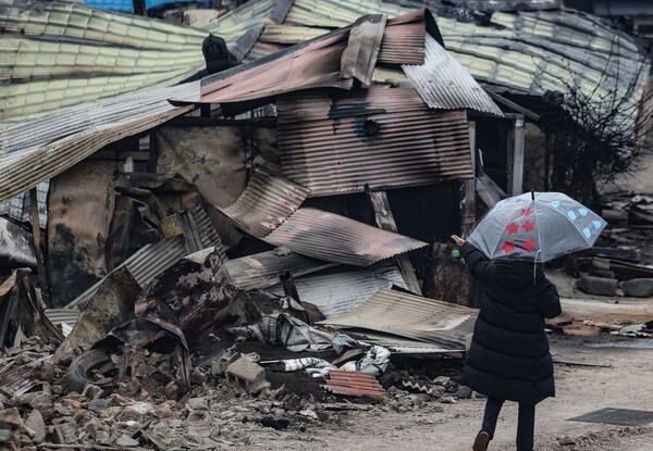 27일 경북 영덕군 지품면 원전리 산불 현장에 내리는 비에 한 주민이 우산을 쓰고 있다. / 사진=연합뉴스