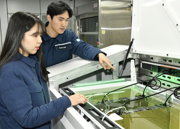 액침냉각설비에 담긴 냉각유와 서버를 테스트하고 있는 HD현대오일뱅크 직원들.