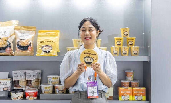 '2025 디지털 유통·물류대전'에 참가한 대한식품 한윤경 대표가 자사 제품을 들고 포즈를 취하고 있다.