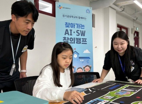 참가학생이 CJ올리브네트웍스 임직원 강사들과 함께 자신이 코딩한 자율주행차의 이동경로를 확인하고 있다.