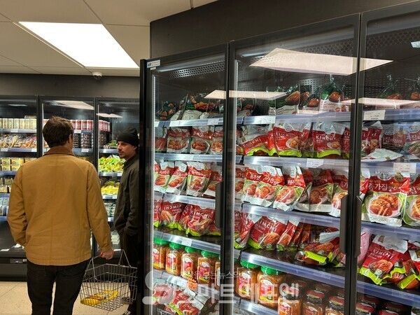 종가집 김치 앞에서 한참 고민하다가 튀김가루를 장바구니에 넣고 이동하는 현지인의 모습./사진=김선주 기자 